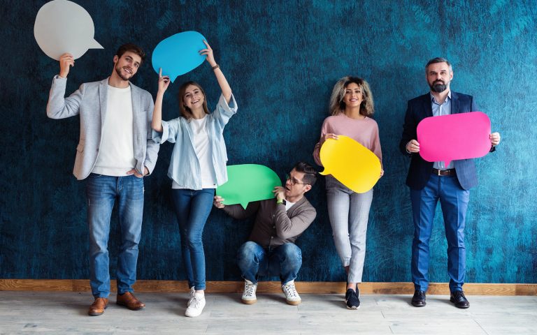 Let's start a conversation. We speak the language of success. Diverse group of businesspeople holding up speech bubbles while they wait in line
